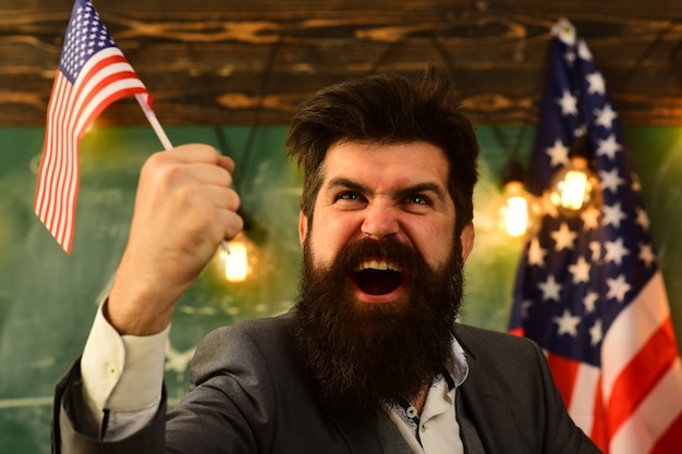 Expressieve zakenman met Amerikaanse vlag in opgeheven hand.