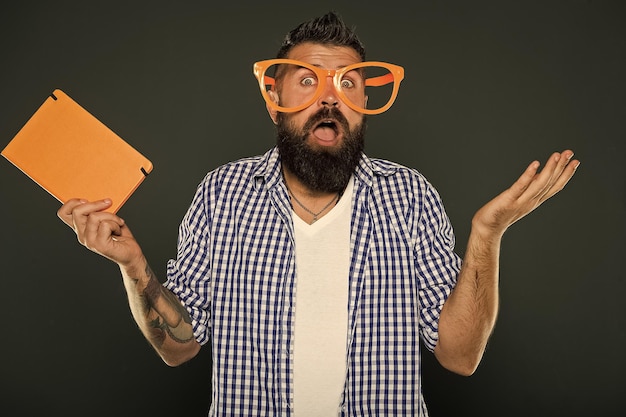 Expressing wonder Book nerd making a helpless gesture University male student wearing fancy glasses with lecture notes Bearded man in party glasses with lesson book Study nerd holding book