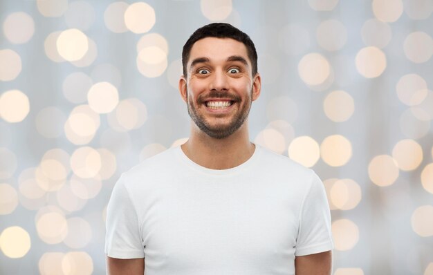 expression, emotions and people concept - man with funny face over holidays lights background