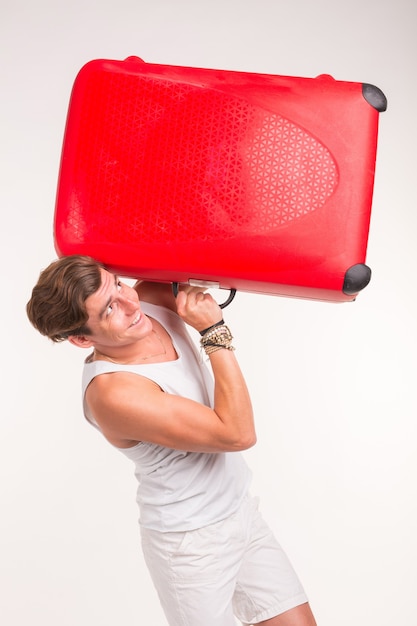 Expression and gesture concept - Young man in white shirt holding red suitcase