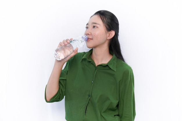 Expression of Indonesian Asian woman in green dress drinking water in a bottle