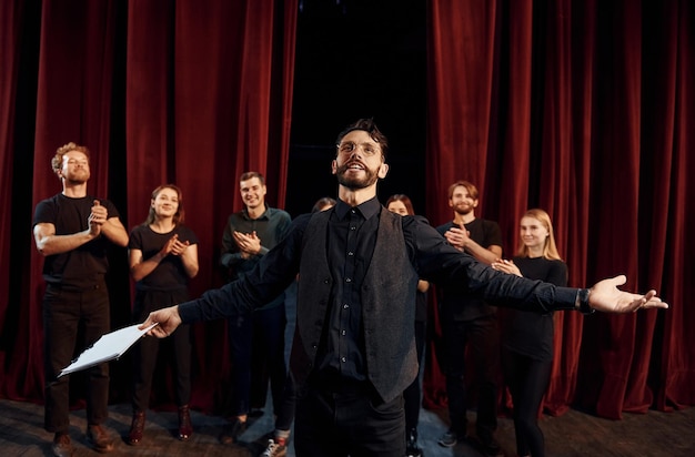 Expressionele kerel die zijn rol oefent groep acteurs in donkere kleding tijdens repetitie in het theater