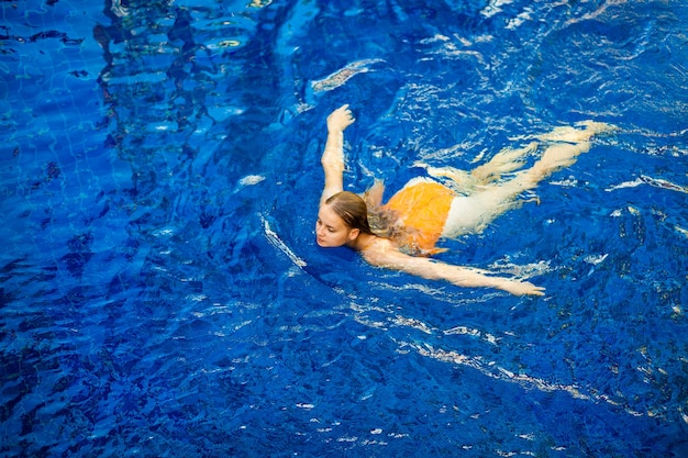 Expressive beautiful woman posing in the swimming pool