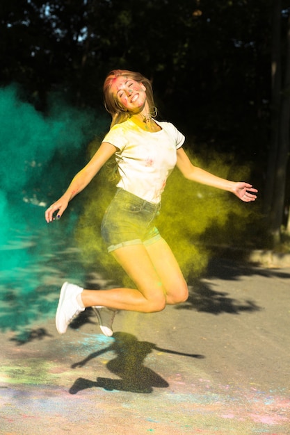 Expressive blonde woman jumping with vibrant colors exploding around her