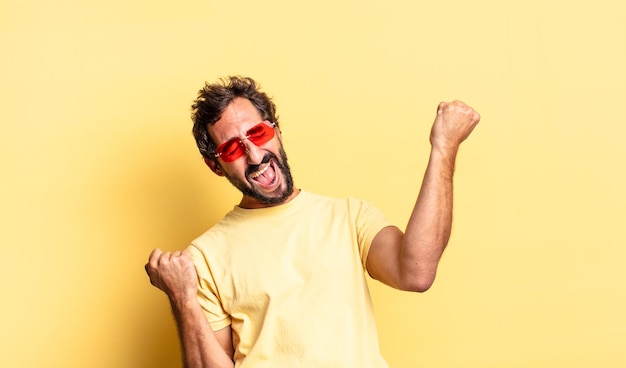 Expressive crazy bearded man wearing sunglasses with a copy space against yellow wall