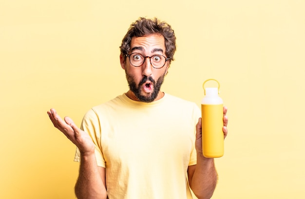 Expressive crazy man amazed, shocked and astonished with an unbelievable surprise with a tea thermos