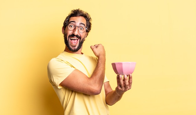 Expressive crazy man feeling happy and facing a challenge or celebrating and holding a pot