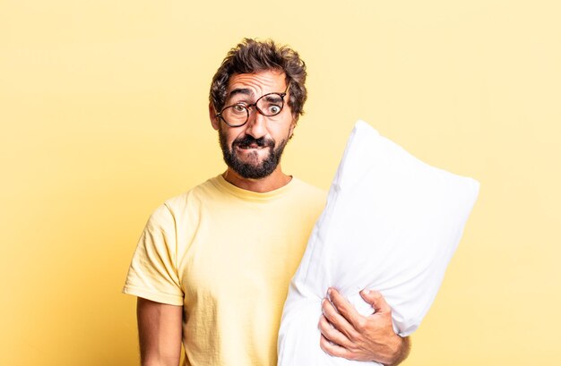 Expressive crazy man looking puzzled and confused and holding a pillow