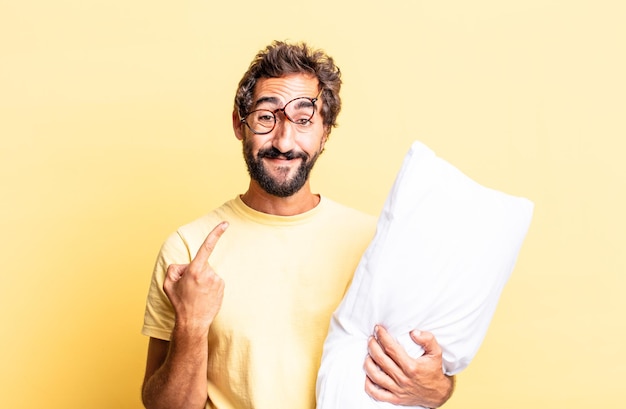 Expressive crazy man smiling confidently pointing to own broad smile and holding a pillow