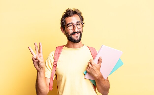 Expressive crazy man smiling and looking friendly, showing number three. adult student concept