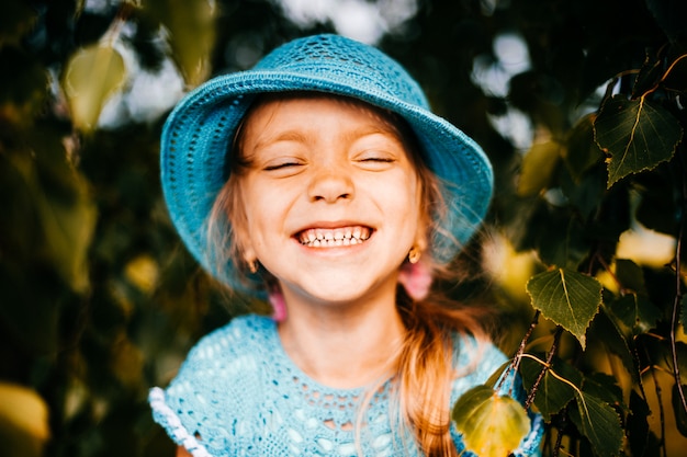 Expressive face of smiling little girl in blue clothes