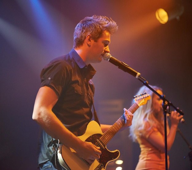 An expressive frontman singing and playing guitar at a gig The best live performance concert