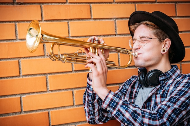 Expressive hipster man Hitting Trumpet Note.