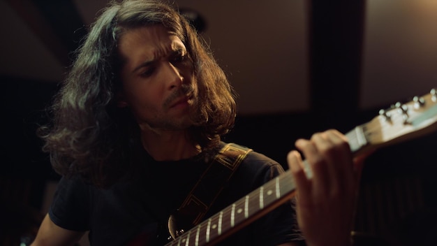 Expressive man playing guitar in studio Guitarist gesticulating in hall