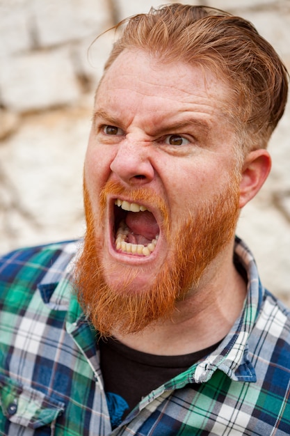 Expressive red haired hipster man with blue plaid shirt 