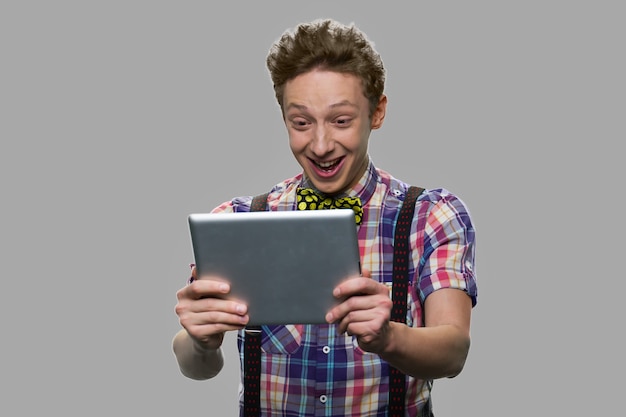 Expressive teenage boy having video call. Trendy teen guy having video chat against gray background. People, technology, internet communication.