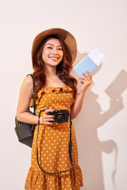 Photo expressive tourist woman in summer casual clothes hat holding passport tickets isolated on beige background female traveling abroad to travel weekends getaway air flight journey concept