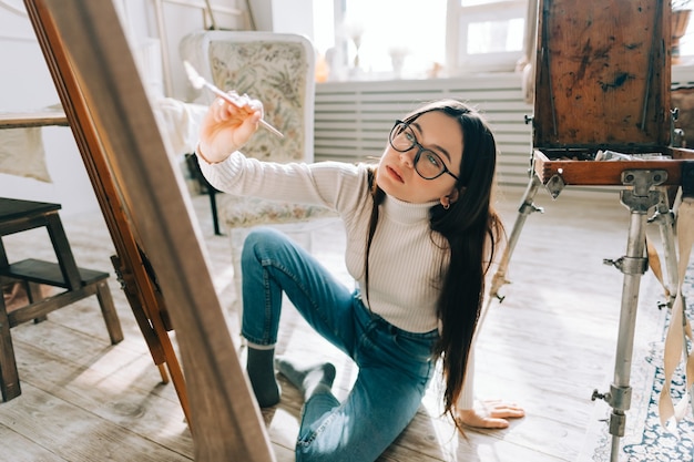 Photo expressive young artist woman painting on canvas