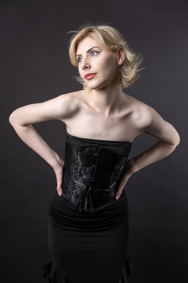 Expressive young blonde under a bob in the studio In a black corset and dress