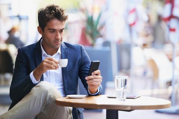 Expresso break Shot of a young businessman reading a text while sitting at an outdoor cafe