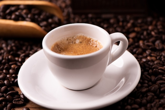 Чашка кофе экспрессо крупным планом над темными жареными кофейными зернами
