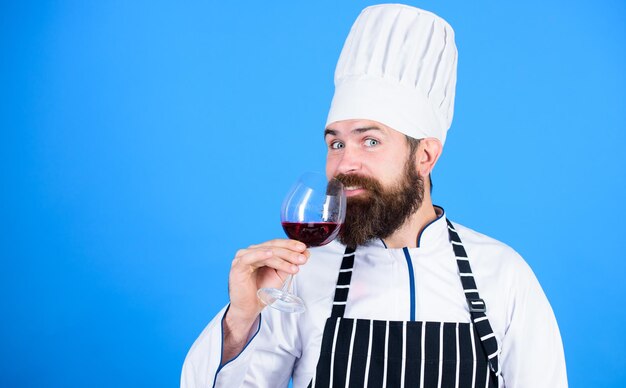 Exquise dinerconcept Wijndegustatie Hoe wijn en eten te matchen als een expert Man draagt hoed en schort geniet van het aroma van een drankje Hipster-kok houdt een glas wijn vast Welke wijn te serveren bij het diner