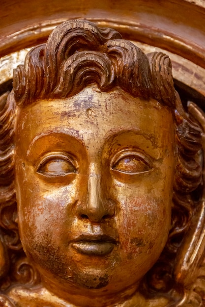 Exquisite golden wood carvings on the face of a child inside a Christian church.