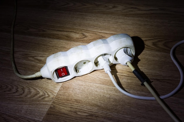 Extension cord and wires on wooden floor in dark