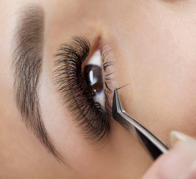 Extension of the lower eyelashes. a young woman undergoes a close-up eyelash extension procedure. Tweezers. Down below