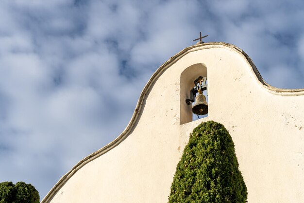 Foto campana esterna sulla facciata di un eremo con un cielo blu nuvoloso