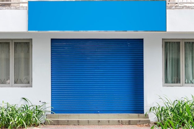 食料品店の空白の看板と閉じた青いシャッターローラードアの外観