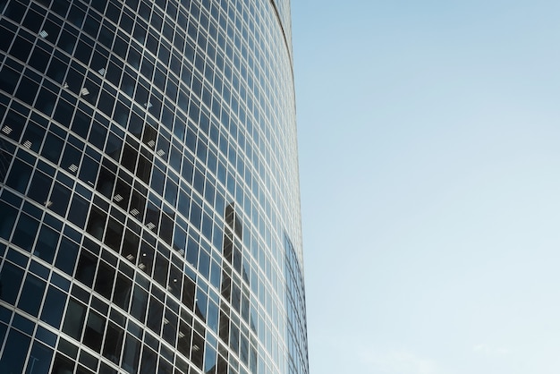 Exterior of a modern high-rise office building against a clear blue sky. Close-up of a skyscraper in the city center. Business and finance concept.