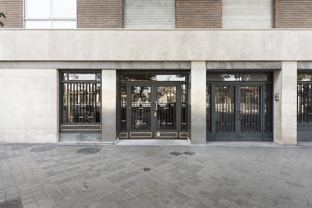 Exterior portal to the street of a simple residential building with painted metal doors and golden details