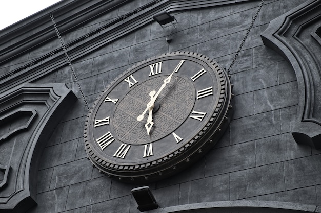 Exterior roman numeral clock on facade of building. Antic vintage clock in railway station.