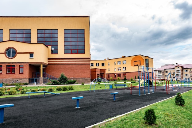 Photo exterior view of modern public school building with playground.