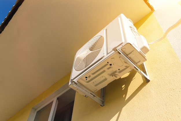 External air conditioner mounted outside on the house wall close-up view photo