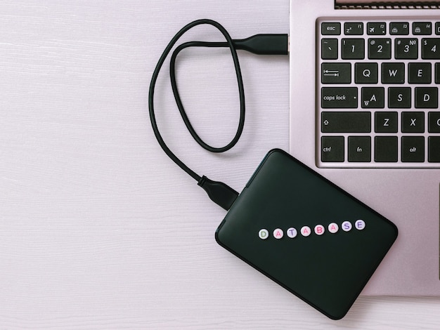 External hard drive connected to laptop on a white table. The view from the top. The concept of backup storage. Flat lay.