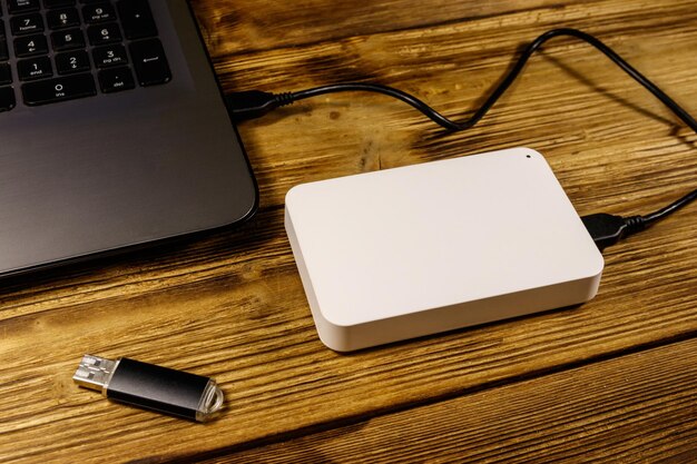 External HDD connected to laptop computer and USB flash drive on a wooden desk Concept of data storage