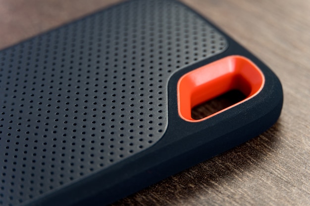 An external SSD Drive isolated on wooden background. Selective focus. Macro.