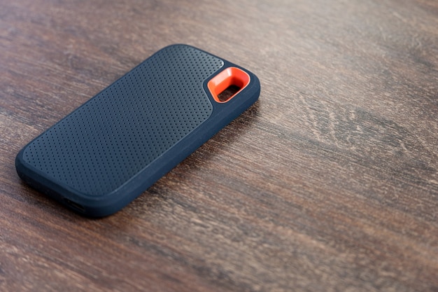 an external ssd drive isolated on wooden background. selective focus.