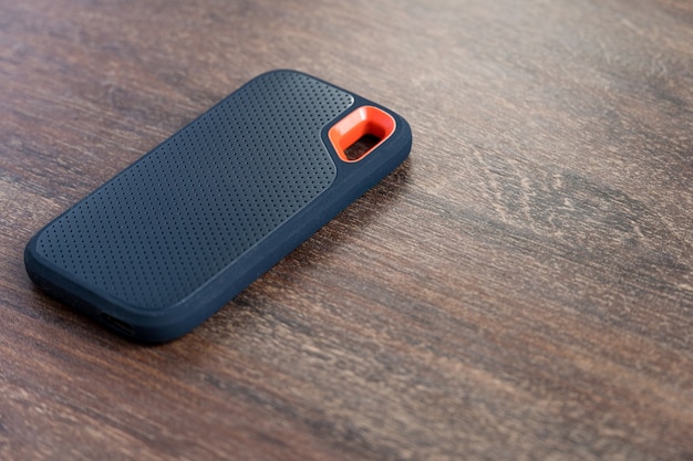 An external SSD Drive isolated on wooden background. Selective focus.