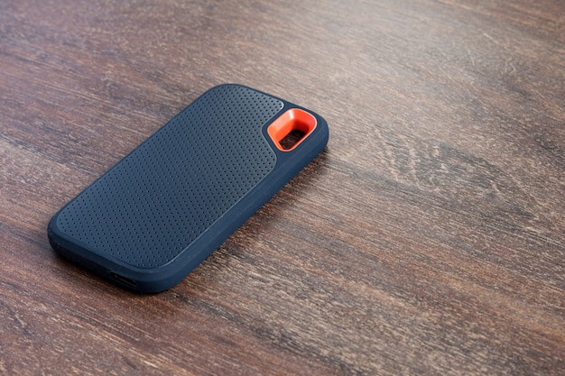 an external ssd drive isolated on wooden background. selective focus.
