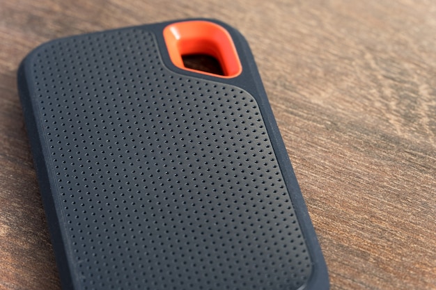 an external ssd drive isolated on wooden background. selective focus.