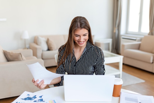 Externe baantechnologie en mensenconcept gelukkig lachende jonge zakenvrouw met laptopcomputer en papieren die thuis werken tijdens de Covid19-gezondheidscrisis