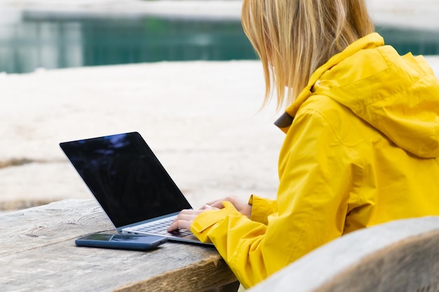 Externe werknemer die ontspant in de buurt van het meer en een laptop gebruikt die werkt of studeert via een laptop en smartp