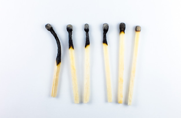 An extinct match in a man\'s hand. death and aging concept.\
burned matches in a row on a white background. burnout.