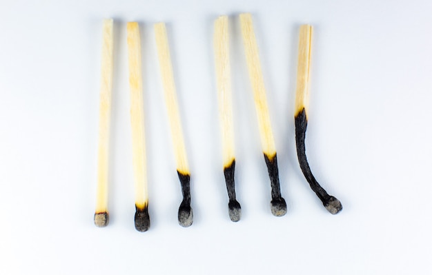 An extinct match in a man's hand. Death and aging concept. Burned matches in a row on a white background. Burnout.