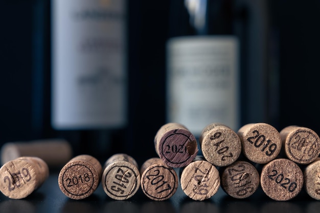 Photo extracted wine corks with vintage year 2015 to 2020 imprint with two bottles in dark background
