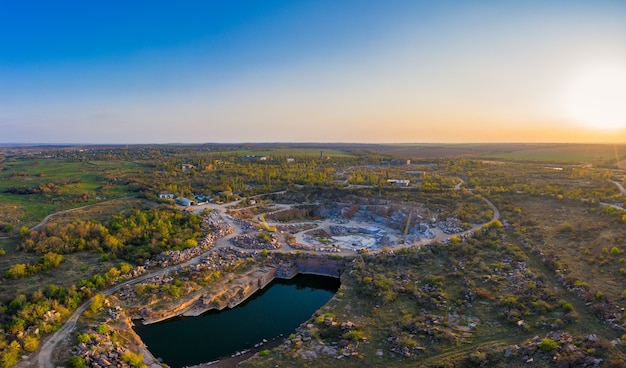 Estrazione di minerali con l'aiuto di attrezzature speciali vicino a un piccolo lago nella calda luce della sera nella pittoresca ucraina