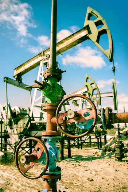 Extraction of oil. Wellhead with valve armature and pump jack. Toned.